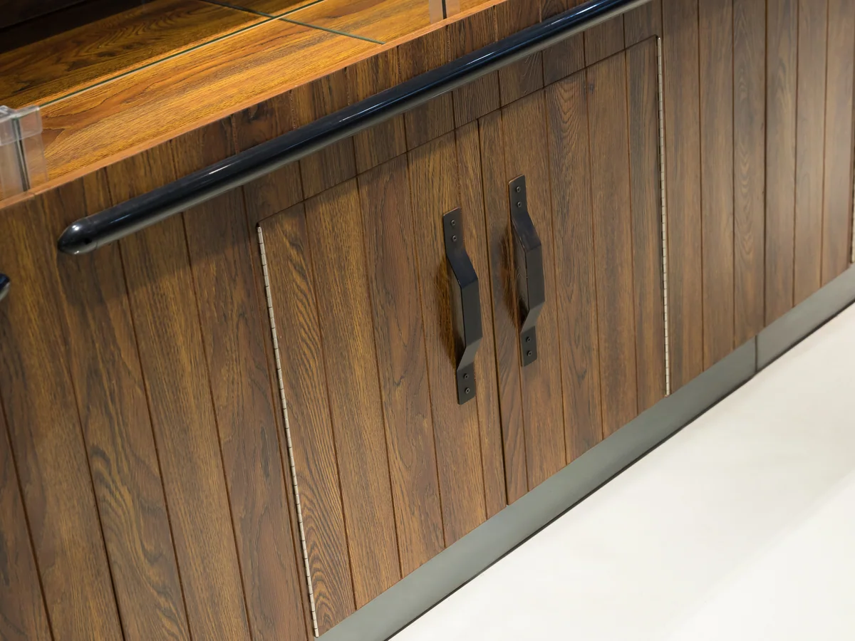 Close-up of the dark timber cabinet doors with long black bar handles
