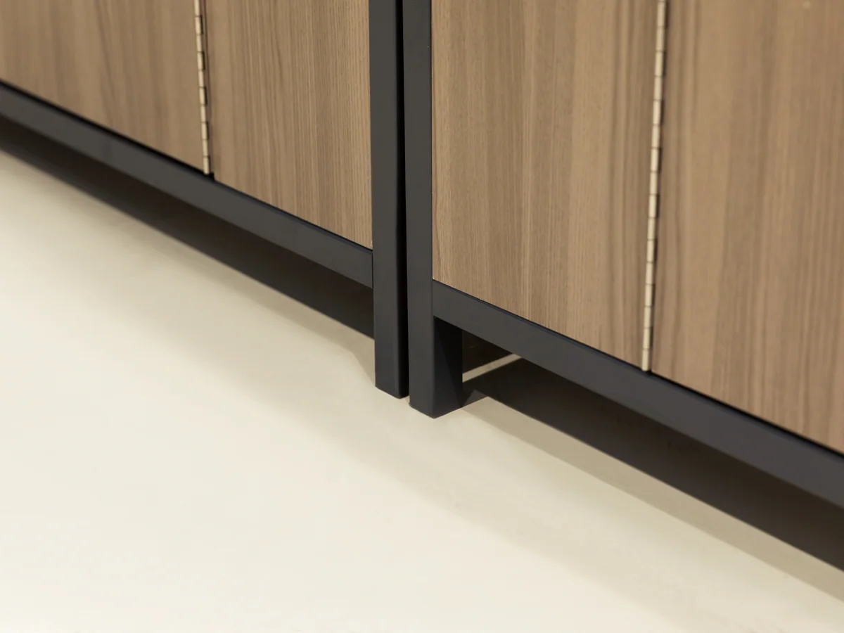 Close-up of the junction between the black plinth and the timber cabinet run