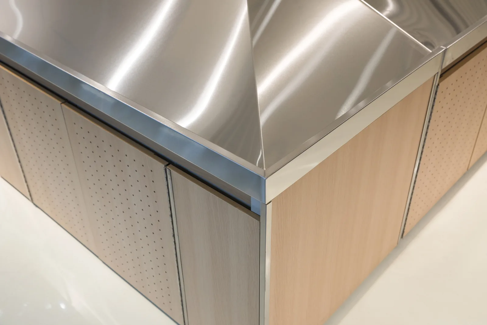 Detail of the stainless steel top meeting the wood fascia and aluminium trim on a Keshun produce island