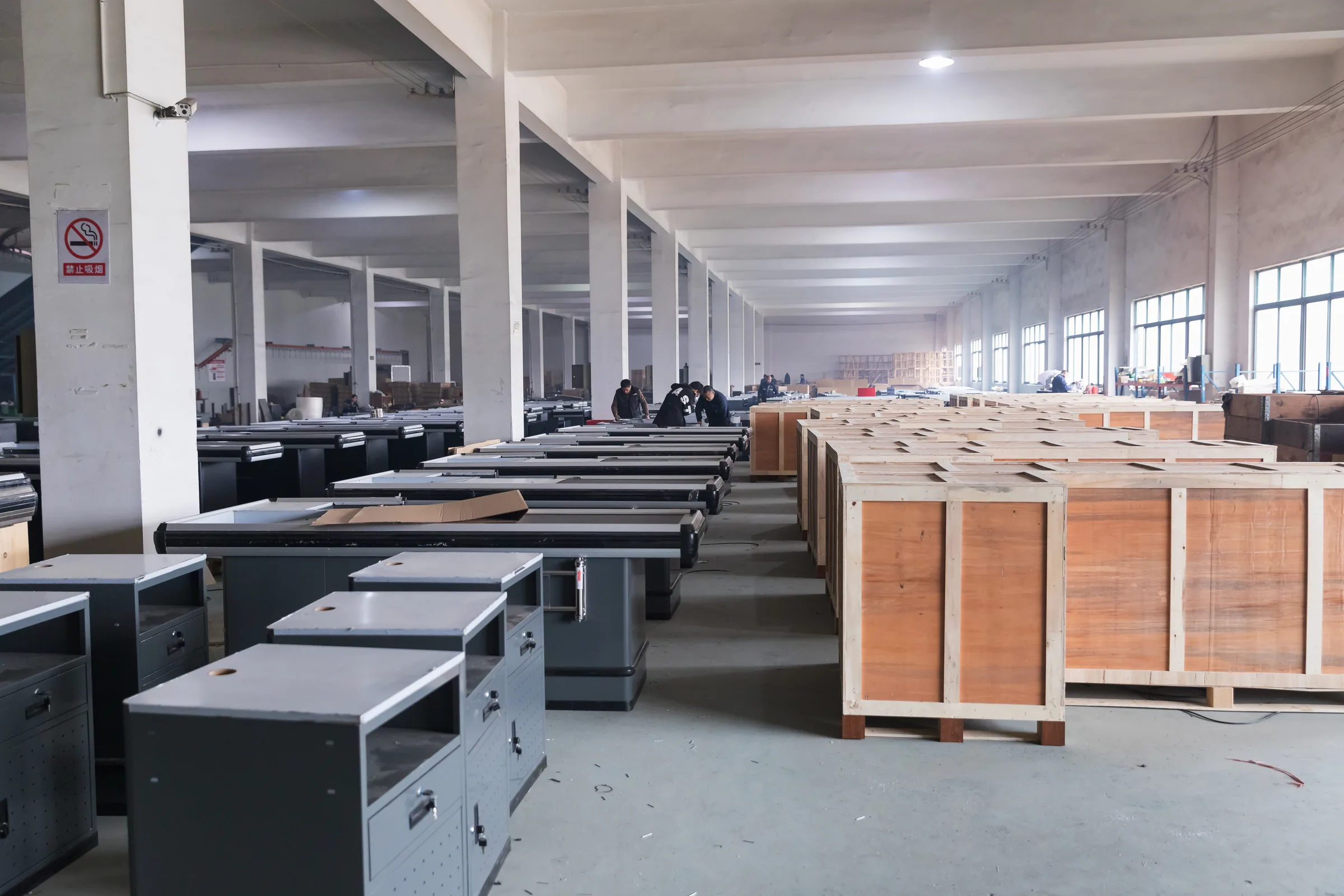Finished checkout counters and display cabinets lined up along an aisle of the Keshun supermarket equipment factory