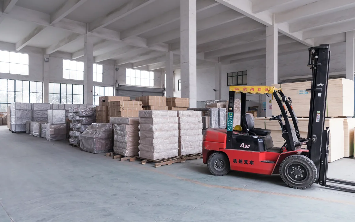 Forklift moving palletised and crated supermarket fixtures inside the Keshun plant