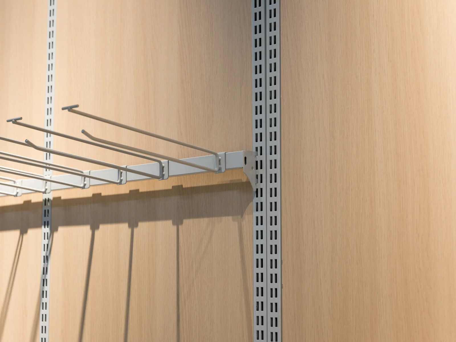 Wall produce rack photographed straight on, showing the angled arms above the stainless table
